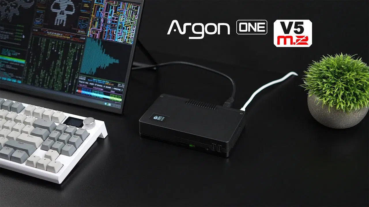 Boîtier Argon One V5 M.2 posé sur un bureau entre un clavier et un écran de code